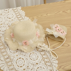 Détail d'un chapeau de paille et sac avec fleurs roses et nœuds en dentelle enfant