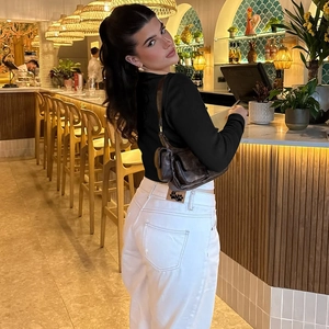 Photo lifestyle d'un cardigan noir boutonné associé à un pantalon large blanc chic