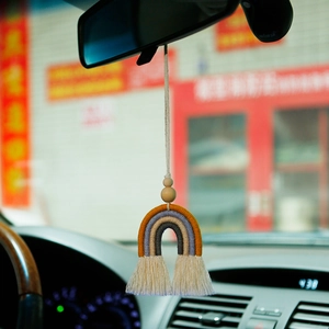 Handmade macrame rainbow car charm with wooden beads hanging from a rearview mirror
