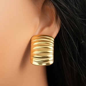Close-up of golden geometric rectangle earrings with wavy texture on female model