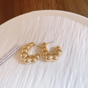 Close-up of golden C-shaped croissant hoop earrings with a textured pleated finish