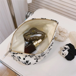 Detail view of large canvas makeup bag with floral print and metal zipper closure