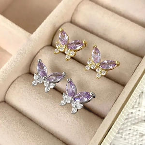 Close-up of gold and silver butterfly stud earrings with purple zircons in a jewelry box
