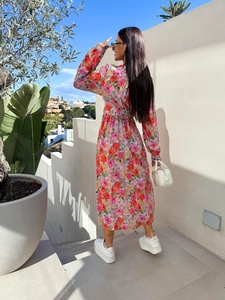Outdoor back view of a long-sleeved floral maxi dress with waist tie and vibrant patterns