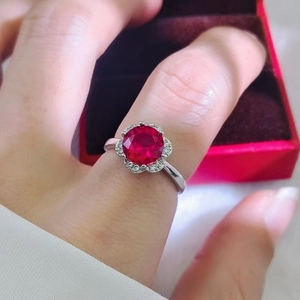 Close-up of a 2-carat floral ruby ring with a sparkling halo setting on a silver band