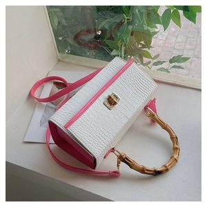 Detail of white crocodile pattern handbag with bamboo handle and pink shoulder strap