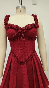 Detail of burgundy lace dress featuring ruffled straps and front drawstring lace-up design