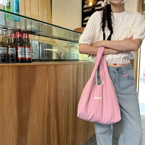 Close-up of pink pleated fabric tote bag with a white minimalist woven logo label
