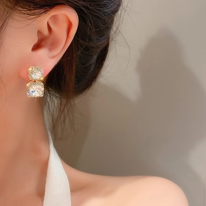 Close-up of elegant double square rhinestones earrings with gold plating on ear lobe