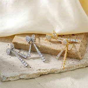 Nahaufnahme eleganter Schleifen-Ohrringe mit Quasten in Gold und Silber mit Zirkoniasteinen