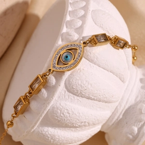 Detailed close-up of 18K gold evil eye bracelet with white zircons on a white plaster art