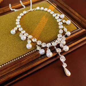 Detail of silver drop pearl necklace with sparkling rhinestones on green velvet display
