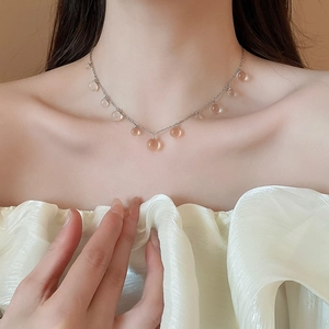 Gros plan d'un collier chaîne argenté avec pendentifs en perles de résine sur la clavicule