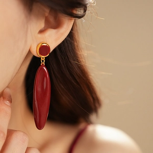 Gros plan sur des boucles d'oreilles pampilles ovales rouge foncé et métal doré poli