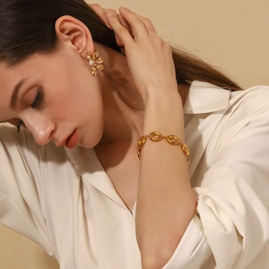 Close-up of vintage 18K gold plated flower earrings with pearls and hollow ring bracelet