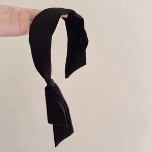 Elegant black satin headband with long flowing ribbons for a vintage minimalist French look