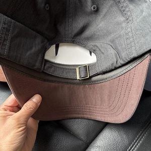 Detail of adjustable metal buckle and contrast stitching on dark gray baseball cap