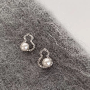 Glistening zirconia and pearl gourd stud earrings on soft grey knit fabric