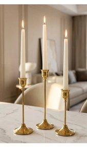 Detalle de tres candelabros dorados sobre mesa de mármol blanco con iluminación suave