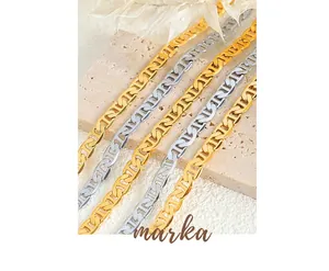 Close-up of gold and silver plated mariner link chains on elegant marble and leaf decor
