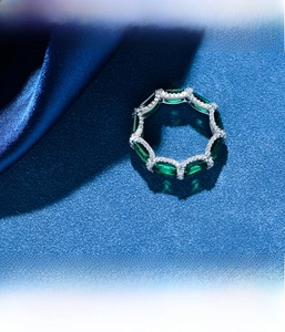 Detail view of S925 silver eternity ring with emerald-cut green gems and micro-pave diamonds