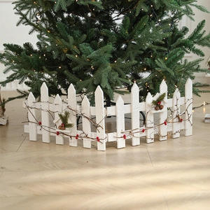 White wooden Christmas fence with red berries and green vines for tree base decoration