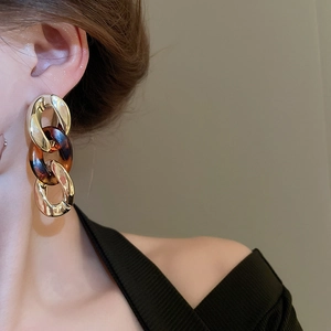 Close-up of leopard resin links and golden chain earrings worn by a female model
