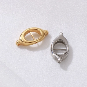 Polished gold and silver curved double-loop stainless steel connectors on textured fabric