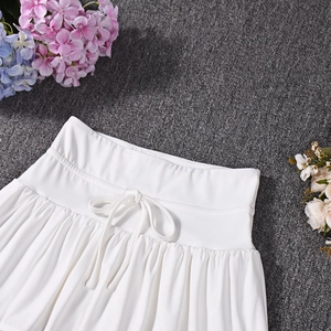 Detailed view of white pleated skirt waist featuring an elastic band and a small bow tie