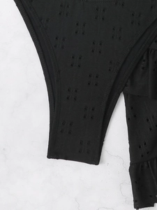 Detailed view of black hollow-out fabric with delicate ruffle edges and geometric texture