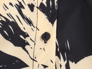 Close-up of black and white printed fabric texture with a round button on shirt dress
