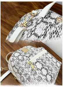 Detail of durable gold metal hooks and detachable white shoulder strap on snakeskin backpack