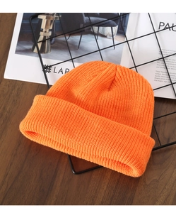 Close-up of bright orange knitted beanie showing detailed yarn texture and craftsmanship