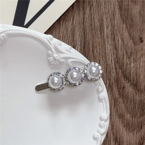 Detailed view of silver hair clip with large white pearls and rhinestone circles