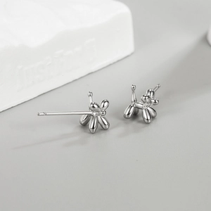 Polished silver balloon dog stud earrings on a modern minimalist aesthetic display