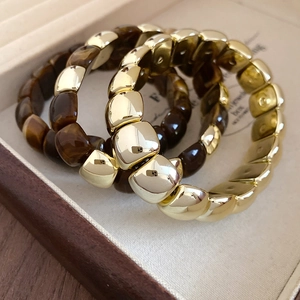 Detail view of square acrylic and gold metal beaded bracelets in a jewelry box