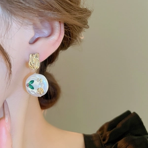 Detailed close-up of vintage resin flower earring with green leaf and gold floral inlay