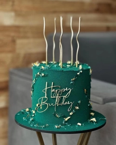 Close-up of golden Happy Birthday acrylic cake topper on green velvet texture cake