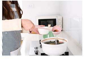 Action shot of dual-purpose wheat straw soup ladle and colander straining food in a white pot