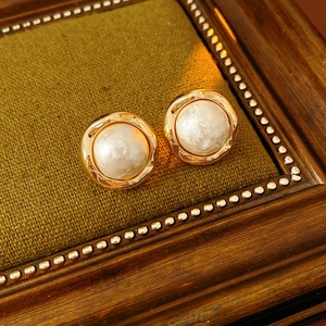 Detailed shot of round gold-plated cotton pearl earrings with retro French design
