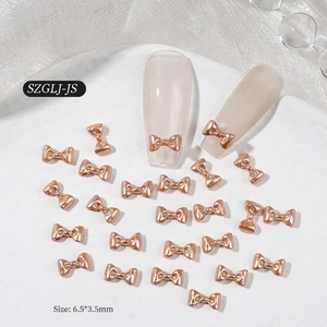 Close-up of 6.5x3.5mm rose gold mini bow nail charms for professional manicures