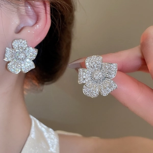 Macro detail of silver flower stud earrings with sparkling crystals and full pave petals