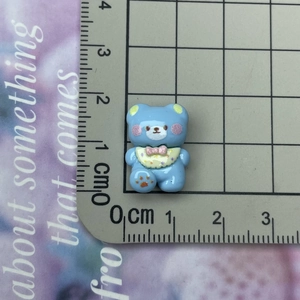 Size demonstration of a mini blue resin bear charm showing 2.5cm height on a scale mat