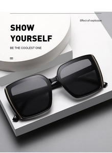 Detailed close-up of black square sunglasses with decorative gold metal side accents