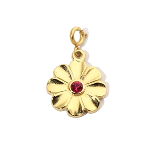 Detail shot of golden flower pendant featuring a central red gemstone on white background
