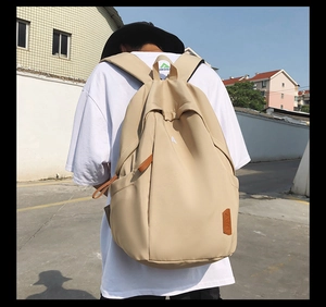 Outdoor shot of a beige large capacity nylon backpack worn by a person from a side view