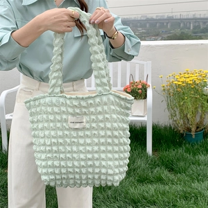 Detail of light green popcorn texture tote bag with LOVE SOZAKKA label in outdoor setting