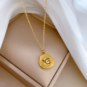 Minimalist gold titanium steel necklace featuring a round elephant charm on beige silk