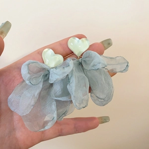 Detailed shot of floral earrings with light green resin hearts and blue mesh bow pendants