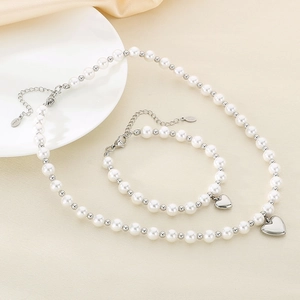 Detailed view of pearl and stainless steel jewelry set with heart-shaped pendants
